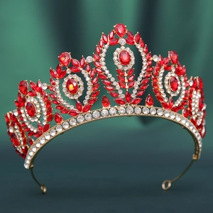 Close-up of golden Baroque crown with red water-drop crystals on green fabric