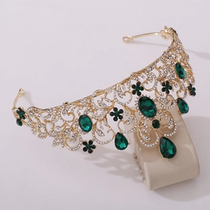 Macro view of gold bridal tiara with green emerald stones and white rhinestones