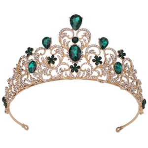 Close-up of golden bridal crown with emerald green rhinestones and leafy vine design