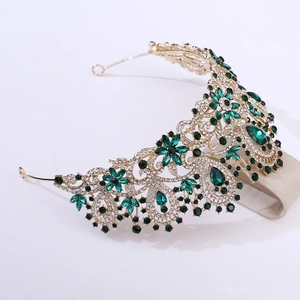 Macro detail of luxury baroque gold crown with emerald green gems and white rhinestones