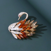 Macro shot of the elegant golden swan brooch featuring multi-colored crystal wings