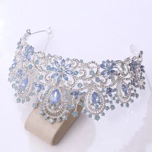 Detailed close-up of a silver bridal crown with light blue gemstones and crystals on a stand