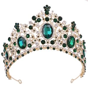 Close-up of golden crown with emerald green gems and sparkling white rhinestones