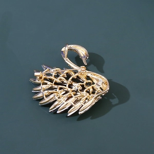 Detailed back view of golden swan brooch showing pin clasp and hollow metal craft