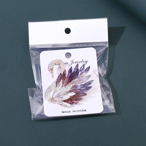 Detail of elegant gold-tone swan brooch with colorful crystals in its original packaging