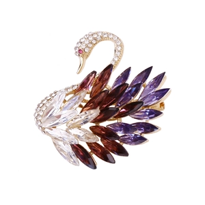 Elegant gold swan brooch with purple and amber crystals on white background