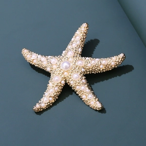Vue macro d'une broche étoile de mer avec perles et métal doré sur fond sombre élégant