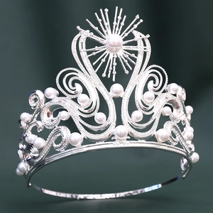 Luxury silver tiara with white pearls and sparkling crystals on a green background