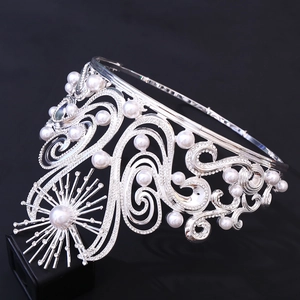 Detailed close-up of Baroque silver crown with intricate scrolls and white faux pearls
