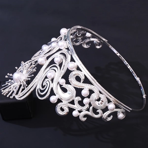 Macro view of silver baroque bridal crown featuring white pearls and rhinestone scrolls