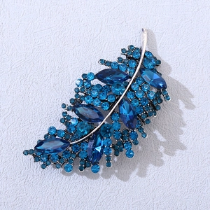 Macro di una spilla a foglia in cristallo blu con base argentata e strass luminosi