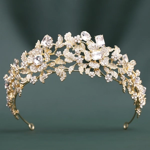 Elegant gold tiara with white crystals and floral patterns on a dark green background