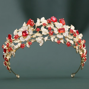 Close-up of golden baroque tiara with red emerald-cut gems and floral rhinestone patterns