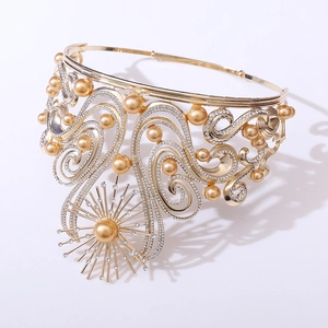 Close-up of golden Baroque crown with white rhinestones and pearls on white background
