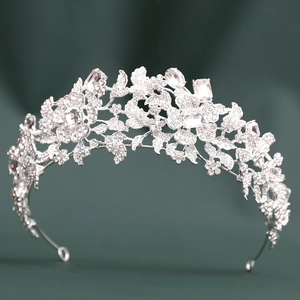 Elegant silver bridal tiara with floral rhinestones on dark green fabric background