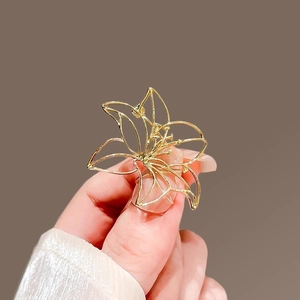 Detailed view of an elegant hollow lily brooch in a polished gold metal finish