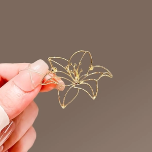 Detail of elegant gold hollow lily flower brooch showing fine polished metallic texture