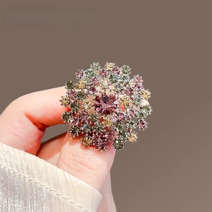 Détail d'une broche pissenlit avec cristaux colorés et une grande pierre centrale mauve