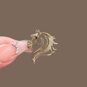 Vue macro d'une broche cheval dorée avec micro-pavage de zircons et œil en gemme noire