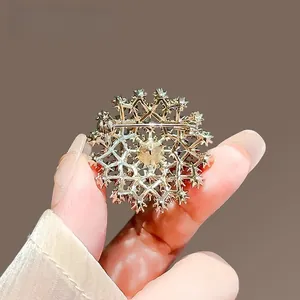Détail d'une broche flocon dorée vintage aux lignes géométriques et fermeture épingle
