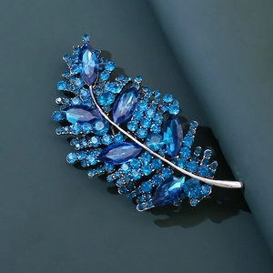 Primo piano dell'elegante spilla a foglia con strass blu scintillanti su base in lega argento