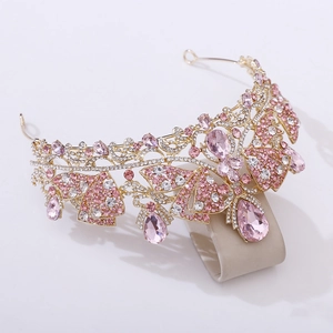 Detailed close-up of a gold bridal crown featuring pink crystals and butterfly accents