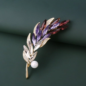 Détail de la broche épi dorée sertie de cristaux violets et d'une perle blanche