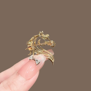 Gros plan détaillé d'une broche cheval dorée ajourée avec des détails en strass brillants