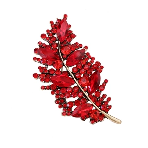 Exquisito broche de pluma dorada con brillantes cristales rojos y pedrería fina