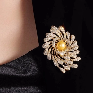 Détail macro de la broche luxueuse en perle dorée et cristaux brillants sur tissu noir