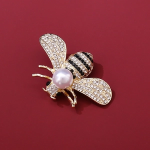 Detailansicht der goldene Bienenbrosche mit glitzernden Strasssteinen und großer weißer Perle