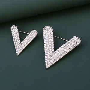 Elegant V-shaped silver brooch set with sparkling white crystals on dark background