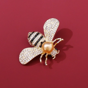 Makro-Detail einer luxuriösen Bienenbrosche mit weißen Kristallen und goldener Perle
