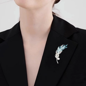 Broche élégante en forme de plume avec pierres bleues et perle blanche sur revers