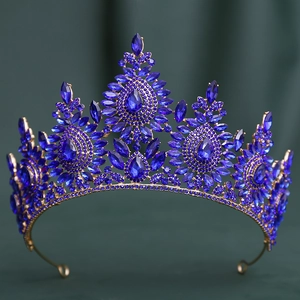 Detail of baroque gold crown with deep blue crystals on dark green velvet background