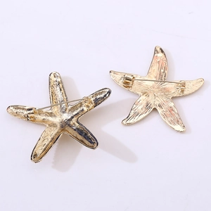 Detail view of the golden metal starfish brooches showing textures and pin clasp back