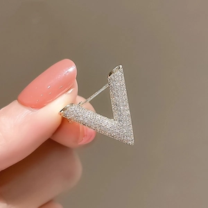 Detail of hand-held gold V-shaped brooch with pave-set crystals for suit decoration