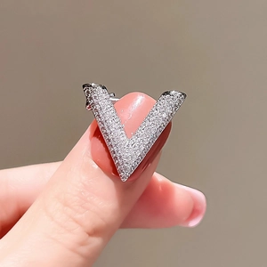 Macro shot of silver V-shaped brooch featuring crystal pavé setting on a finger