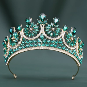 Macro shot of gold wedding crown with emerald green crystals and symmetrical floral details