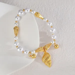 Détail du bracelet en perles avec breloque coquillage doré et accents marins