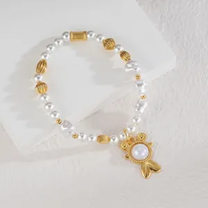 Gros plan d'un bracelet en perles avec breloque poisson dorée sur un support minimaliste