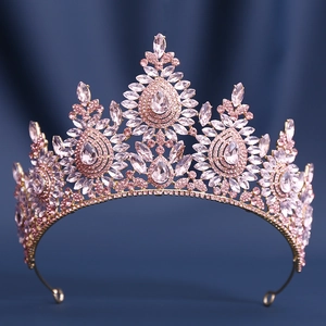 Macro detail of rose gold crown with pink crystals on dark blue velvet background