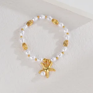 Détail d'un bracelet de perles avec un pendentif étoile de mer doré et des perles en métal