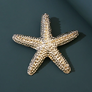 Detailed close-up of a vintage golden starfish brooch with textured metallic finish