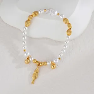 Détail du bracelet en perles avec pendentif poisson doré et clochette sur support