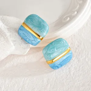 Détail de boucles d'oreilles carrées géométriques avec texture marbre bleu et barre dorée