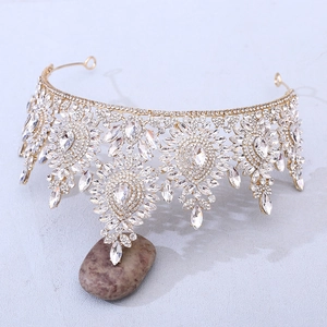 Detail view of gold baroque crown with crystal rhinestones on a blue surface