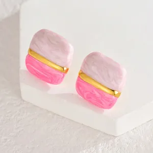 Détail macro de boucles d'oreilles carrées avec texture marbre rose et blanc sur pierre