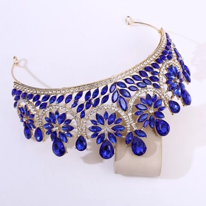 Detailed close-up of a baroque gold bridal crown with deep blue crystals on a display stand