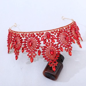 Detail view of ornate golden crown with vibrant red pear-shaped rhinestones and crystals